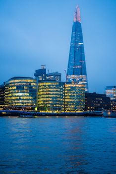 London, UK - January 26, 2017: Vertical photo across the River Thames of the London UK skyline boasting with the Shard glowing in the evening light.