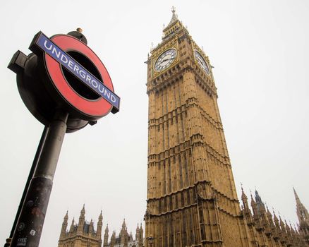 London, UK - February 4, 2017: Juxtaposition of an Underground sign with the Big Ben clock tower. Unique perspective