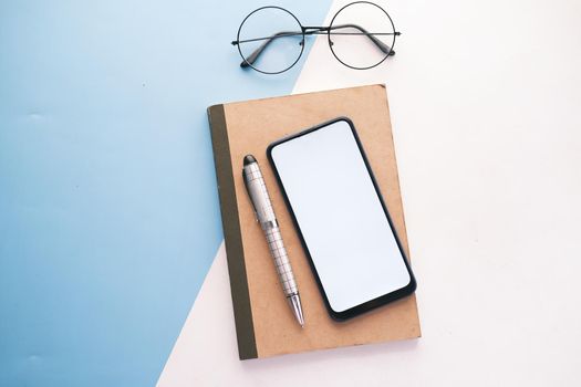 top view of smart phone and notepad on table .