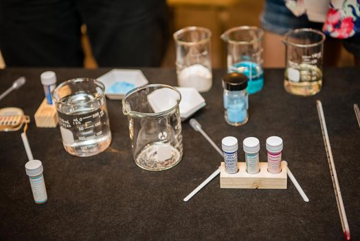 A close up product photo of science experiment materials including colorful liquid filled beakers and various vials and stirring mechanisms.