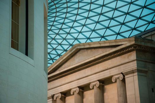 London, UK - February 4, 2017: The British Museum futuristic glass ceiling roof of the Great Court juxtaposed with pillars and other architectural shapes. Unique perspective