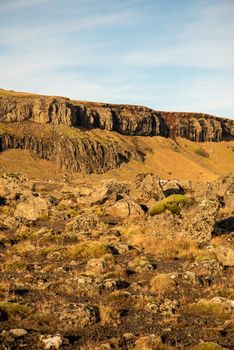 Vertical image of Icelandic topography with warm brown and orange tones and rocky texture with a blue sky