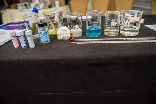 A close up of science experiment materials including colorful liquid filled beakers and various vials and stirring mechanisms.