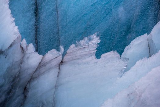 Detail close up of the edge of glacier snowflake like blue and white colors with dark volcanic ash lines