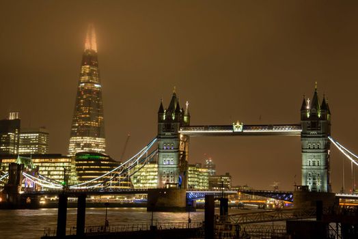 London, UK - January 27, 2017: Tower Bridge and the Shard of London on a foggy evening with glowing lights.