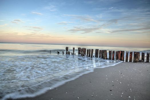 Sunrise over old pier on the ocean at Port Royal Beach in Naples, Florida.