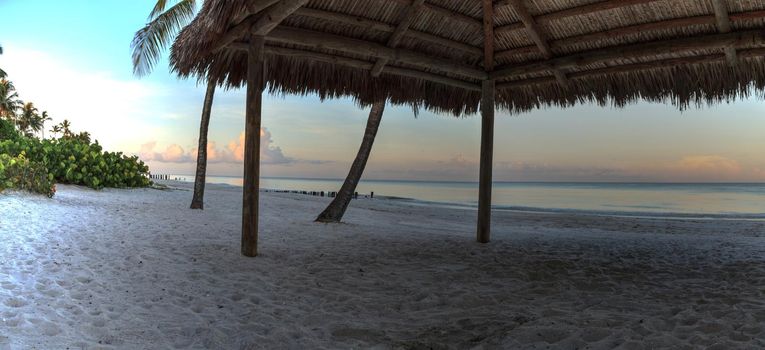 Sunrise over tiki hut on the ocean at Port Royal Beach in Naples, Florida.