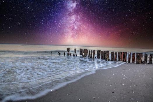 Milky way over old pier on the ocean at Port Royal Beach in Naples, Florida.