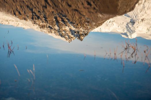 Reflection close up of Icelandic mountain range with beautiful snowcapped mountains reflected into still water. Majestic panoramic view.