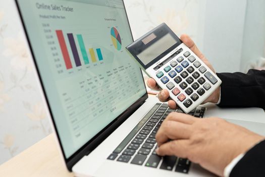 Asian accountant working and analyzing financial reports project accounting with chart graph and calculator in modern office, finance and business concept.