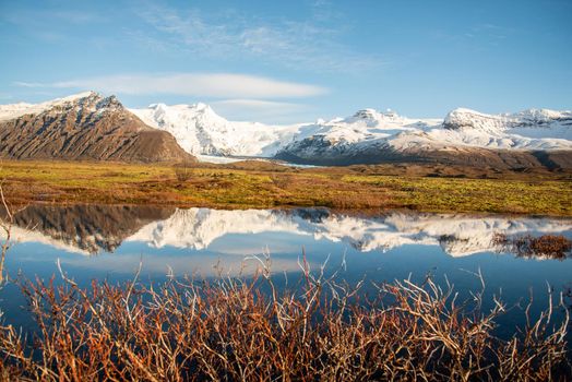 Icelandic mountain range with beautiful snowcapped mountains reflected into still water.