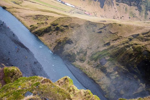 Looking over the edge of a mossy canyon in Iceland where down below you can see a dark river bed.