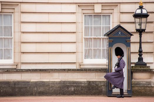 London, UK - January 29, 2017: An action photo from changing of the guards at Buckingham Palace in London with guard marching from phone booth area.