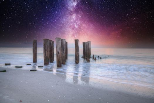 Milky way over old pier on the ocean at Port Royal Beach in Naples, Florida.