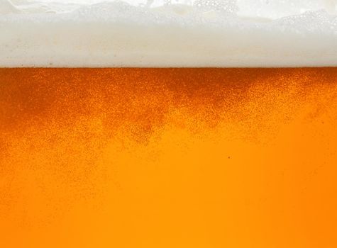 Close up background texture of lager beer with bubbles and froth, pouring in glass, low angle, side view