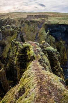 Fjaorargljufur, Iceland mossy green canyon with breathtaking views. Vertical viewpoint of narrow mossy dangerous pathway for canyon views.
