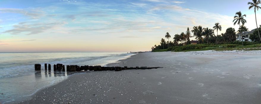 Sunrise over old pier on the ocean at Port Royal Beach in Naples, Florida.