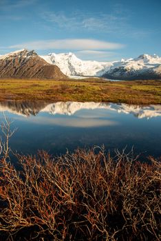 Icelandic mountain range with beautiful snowcapped mountains reflected into still water.