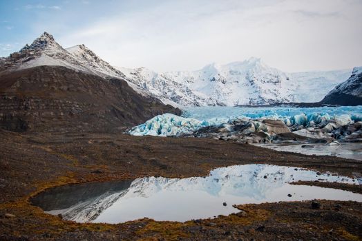 Magical view of Icelandic glacier with layers of iceberg, snow, and melted water with gorgeous reflection.