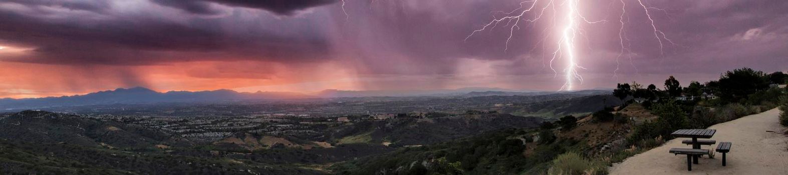 Lightning flashes over the mountains from the Top of the World in Laguna Beach, California at sunrise.