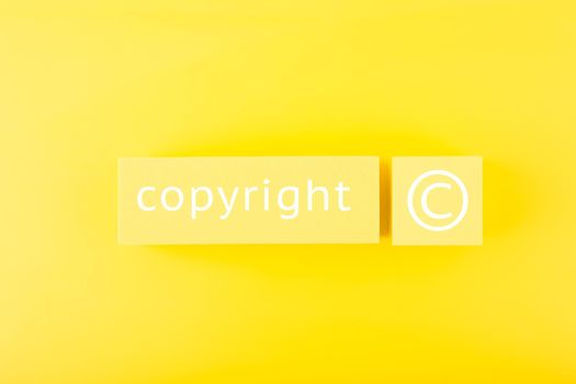 Minimal trendy copyright and patenting concept. Copyright word and symbol on yellow blocks against yellow background