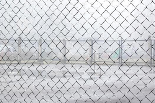 Fence net against the backdrop of a playground for games in the fog