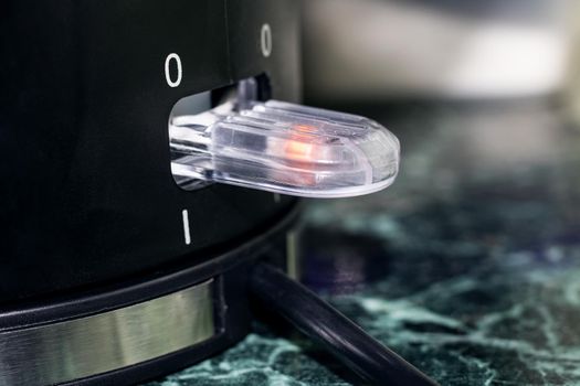 Power button on black electric kettle close up