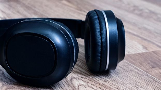 Black headphones on a wooden background close up