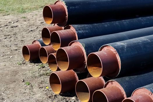 Black metal pipes for water pipes folded on the grass close up