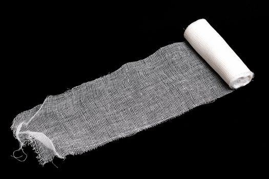Coil of white bandage on a black background close up