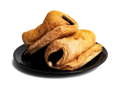 Two buns with chocolate on a black plate isolated on white background