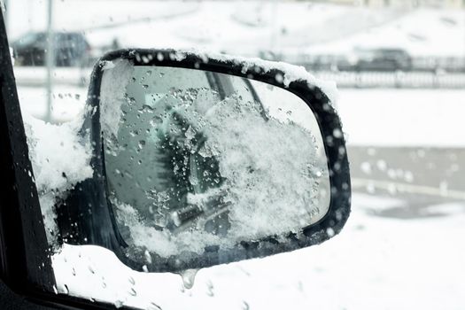 Snow and ice on a side mirror of a car close up
