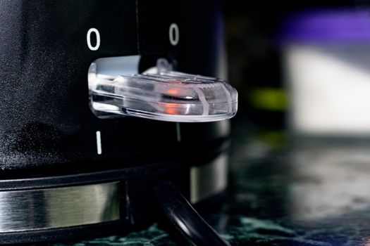 Power button on black electric kettle close up