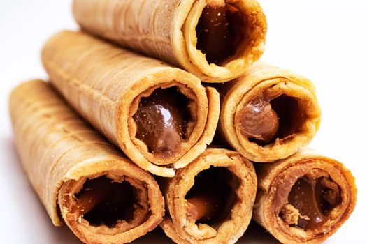 Wafer rolls with condensed milk on a white background close up