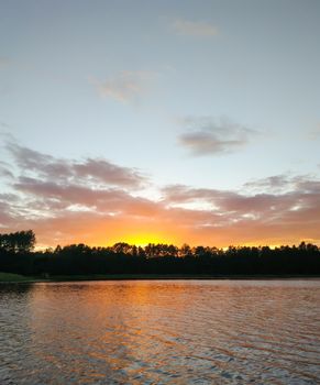 Calm lake surface at evening in Latvia, East Europe. summer sunset landscape with water and forest.