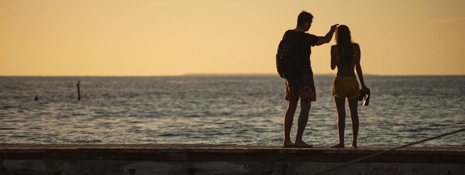 Couple on sunset pier vacation, banner image with copy space