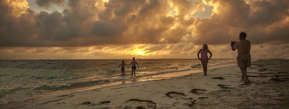 Family in Caribbean beach at sunset, banner image with copy space