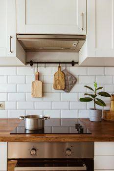 Boiling water in a cooking pot an a pan on a induction stove in the modern white kitchen side view