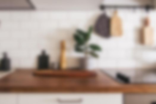 Kitchen brass utensils, chef accessories - blurred kitchen background . Hanging kitchen with white tiles wall and wood tabletop.Green plant on kitchen background side view