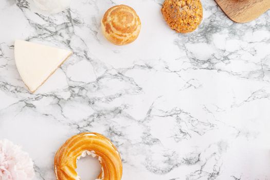 Homemade profitroles pastry filled with custard. Eclairs with cream, French dessert and flowers on marble table top view