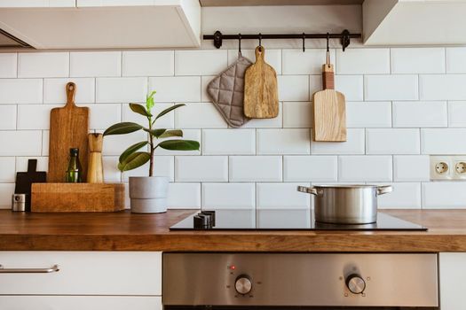 Boiling water in a cooking pot an a pan on a induction stove in the modern white kitchen side view