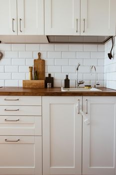 Kitchen brass utensils, chef accessories. Hanging kitchen with white tiles wall and wood tabletop.Kitchen background side view