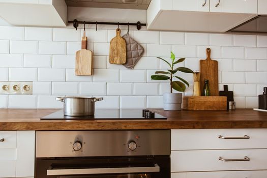 Boiling water in a cooking pot an a pan on a induction stove in the modern white kitchen side view