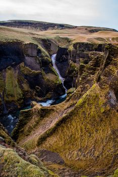 Fjaorargljufur, Iceland mossy green canyon with breathtaking views. Vertical viewpoint of narrow mossy dangerous pathway for canyon views.