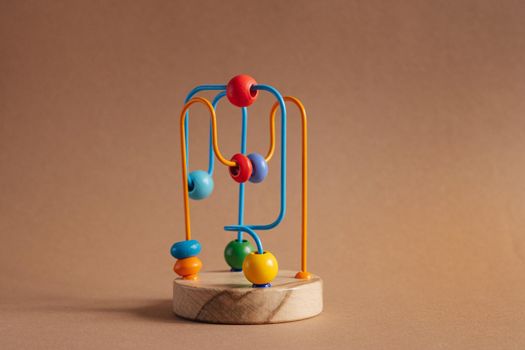 Developing toy for kids. The labyrinth of wooden beads on brown background side view