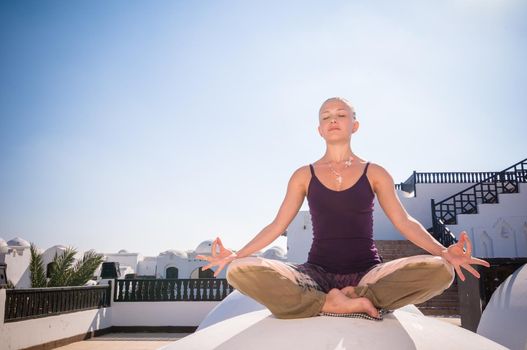 Attractive redhair woman practicing Vinyasa yoga outdoors