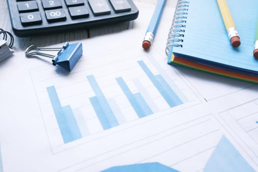 financial graph, calculator and notepad on table.