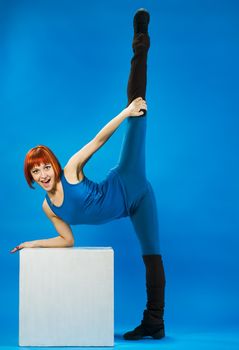 Fit young red haired woman making standing splits stretching
