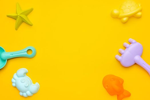 Plastic beach toy pastel color on yellow background. The development of fine motor concept. Creativity Game and summer concept top view