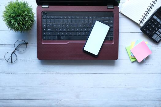 smart phone with empty screen, laptop on wooden background .